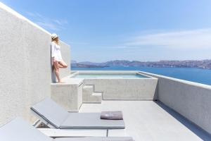 阿克罗蒂里Acroterra Rosa Luxury Suites & Spa的站在带游泳池的房屋阳台的女人