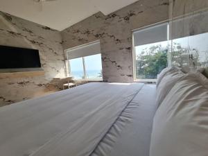 蓬蒂切里Lotus Rooms@Rockbeach的带2扇窗户的客房内的一张白色床