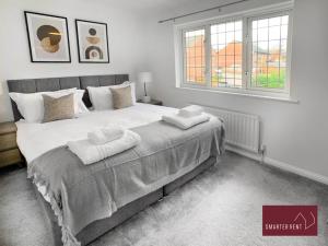BrookwoodKnaphill - 2 Bedroom Terrace House - With Garden的一间卧室配有一张大床和两条毛巾