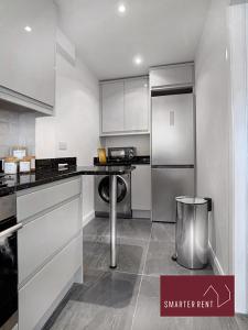 West ClandonGuildford - 2 Bedroom House的厨房配有白色橱柜和冰箱。
