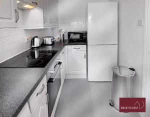 BrookwoodKnaphill, Woking - 2 Bedroom House - Garden and Parking的厨房配有白色橱柜和白色冰箱。