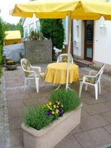乌姆基希Villa Roder的一张桌子、一把伞、两把椅子和鲜花