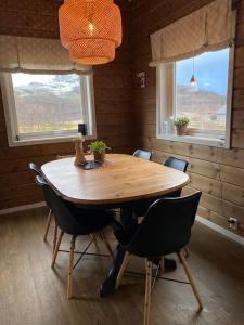 KvalsundHytte i Neverfjord.的带2扇窗户的客房内配有一张木桌和椅子