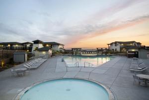 滨海城圣地海滩度假酒店的一个带椅子和日落的大型游泳池