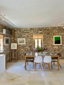 Agia TheodotiThe Artists House - Atelier Suite的一间设有石墙和桌椅的用餐室