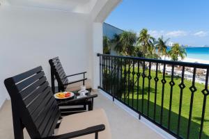 坎昆金哈海滨风景别墅&套房酒店的阳台配有两把椅子,享有海滩美景