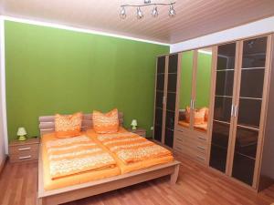 施泰纳赫Ferienwohnung Klaus的绿色卧室配有带橙色枕头的大床