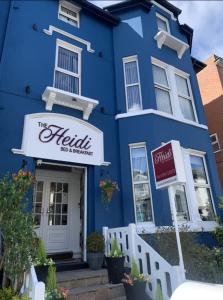 绍斯波特The Heidi Bed & Breakfast的蓝色的建筑,前面有酒店标志