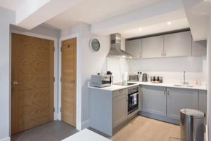 布伦特伍德Modern,central 1 bedroom flat的厨房配有白色橱柜和木门。