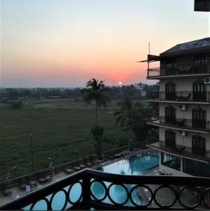 巴加Blue Flamingo Goa Apartment-Casa-Baga的日落前带游泳池的建筑