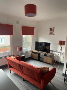 FerryhillQuirky and Cosy Self Contained Flat, Ferryhill Near Durham的客厅配有红色沙发和平面电视