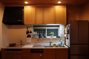 大阪Niji Homestay的厨房配有木制橱柜、水槽和冰箱。
