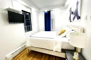 纽约62-2B Renovated 1BR in Prime Upper East Side的一间白色卧室,配有床和电视