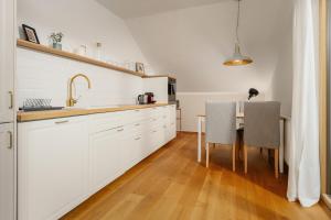 格伦德尔湖Haus Grundlsee的厨房配有白色橱柜和一张桌子及两把椅子