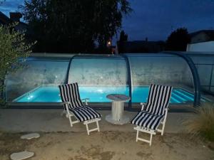 布尔日Chambre bleue avec accès plage的游泳池畔的两把椅子和一张桌子