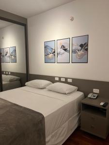圣若泽杜斯坎普斯Flat Premium -Acesso a pé ao shopping Center vale - Edifício Summit (Ar condicionado)的卧室配有一张四幅画的墙壁床。