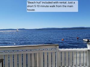 NesoddtangenFlaskebekk at Nesodden with unbeatable Oslo Fjord views and a private beach hut的一张大片水体的画,上面有白色的栅栏