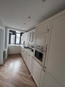 博托沙尼Apartament in Botosani的一间白色的大厨房,配有白色的橱柜和木地板
