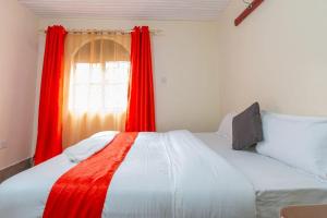 内罗毕City Space Hotel的一间卧室配有一张带红色窗帘的床和一扇窗户
