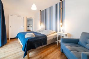 亚斯塔尔尼亚Apartamenty Białe Piaski的一间卧室配有一张床和一张蓝色的沙发
