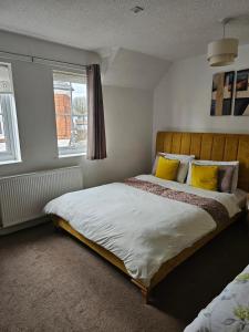塔姆沃思The Gungate的一间卧室配有一张带黄色枕头的床和一扇窗户