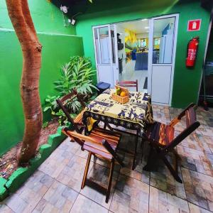 马塞约Pousada Hostel Mar e Sertão的绿墙客房内的桌椅