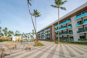 马塞约Maceio Mar Resort All Inclusive的一座配有桌椅的建筑,棕榈树