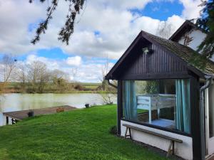 巴讷贡Cottage du Diot, son lac et son île的河边的窗户上带桌子的小小屋