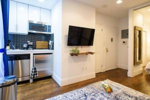 纽约69-3A Prime LES Modern Brand New 1BR的厨房配有白色橱柜和平面电视。