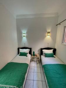 马拉喀什Riad Nour Travel-Les Riads Nour Resorts的配有绿床单的客房内的两张床