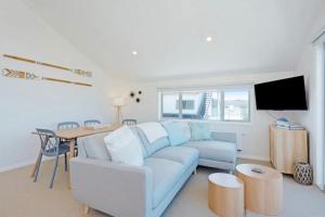 惠灵顿Lyall Bay Parade Apartment的客厅配有蓝色的沙发和桌子