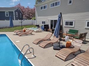 米德尔敦Private Heated Pool - Sparkling Oasis Near Newport & Navy, 4bd 3ba的一组椅子和遮阳伞,位于游泳池旁