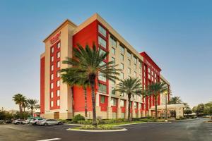奥兰多Drury Inn & Suites Orlando near Universal Orlando Resort的停车场前方的一座棕榈树红色建筑