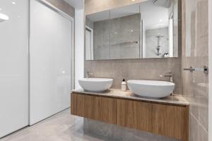 卡瓦纳华特斯Absolute Beachfront 3 Bedroom Penthouse Bokarina Sunshine Coast的浴室内一个镜子,在柜台上有两个水槽