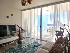 黄金海岸基拉冲浪公寓酒店的一间带电视和玻璃桌的客厅