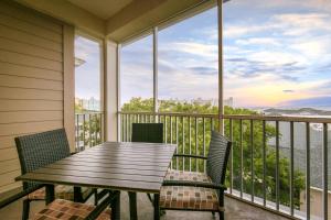 默特尔比奇Holiday Inn Club Vacations South Beach Resort的阳台的门廊配有木桌和椅子