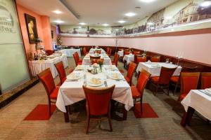斯拉沃尼亚布罗德萨维斯酒店的用餐室配有白色的桌子和红色的椅子