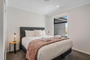 陶波Harakeke Holiday Haven - Taupo的白色的卧室设有一张大床和一个窗户