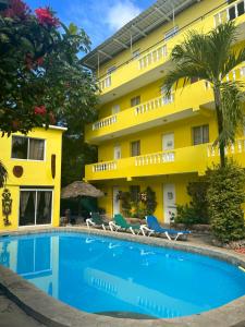 苏莎亚Coco Hotel and Hostel的一座黄色建筑前的带游泳池的酒店