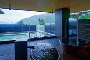箱根Hakone Kowakien Hotel的带浴缸的浴室和游泳池