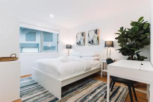贝尔康嫩Lakeside 3-Bed Apartment with Jacuzzi的白色卧室配有白色的床和书桌