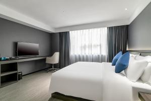 广州迎商酒店(广州广园新村景泰步行街店)的卧室配有带蓝色枕头的大型白色床