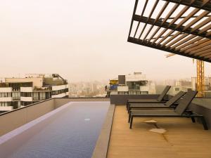 利马Apartamento exclusivo a 70 metros de san Isidro的一个带椅子的阳台和一个位于大楼内的游泳池