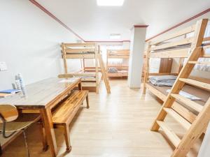 大邱Empathy Guesthouse的客房设有几张双层床和一张桌子。