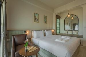 普吉镇Ang Pao Hotel - SHA Extra Plus的卧室配有一张白色大床和一把椅子