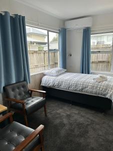 汉密尔顿Avon Apartments的一间卧室设有两张床、一把椅子和一个窗户。