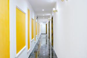 孟买Hotel Gorrion的走廊设有黄色和白色的墙壁,铺有瓷砖地板