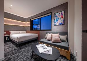 东京HOTEL GRAPHY Shibuya的酒店客房配有床、桌子和沙发。