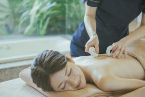 北中城村EM Wellness Kurashinohakko Lifestyle Resort的一位女性从治疗师那里得到按摩