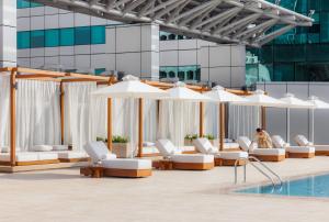 迪拜朱美拉世贸中心住宿、套房及酒店公寓的一个带白色躺椅和遮阳伞的游泳池